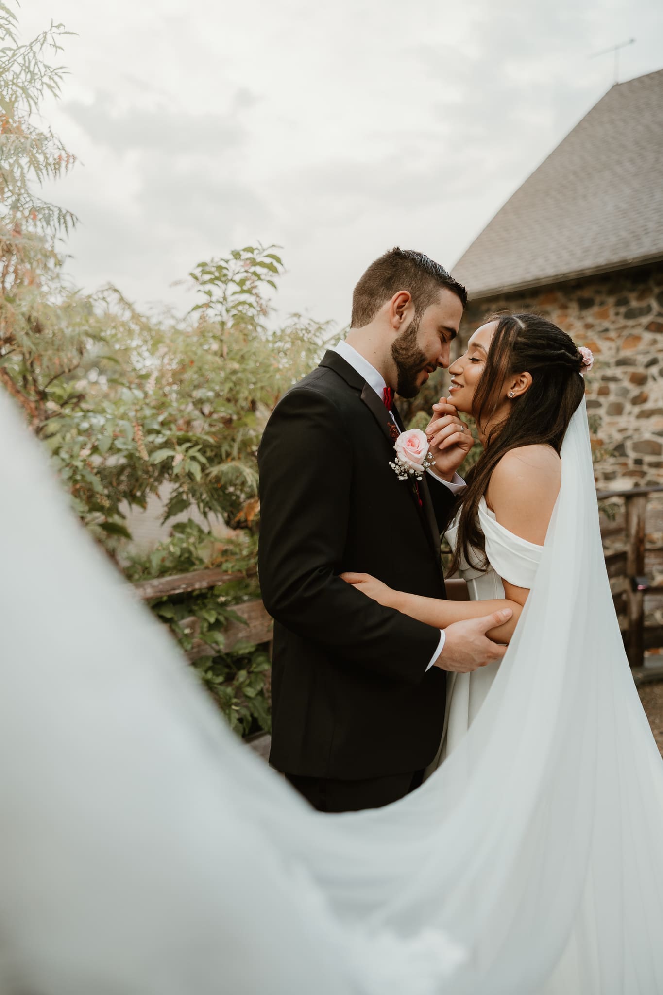 Bride and groom share intimate moment in front of the barn at Tyler Arboretum in Media PA.