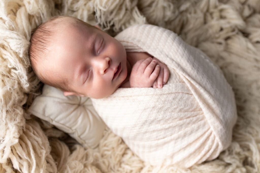 Lehigh Valley Newborn photography in home session with baby in beige swaddle.