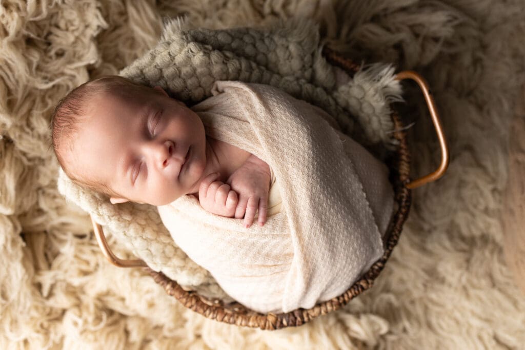 Newborn baby posed with beige flokati for gender neutral in home photography session.