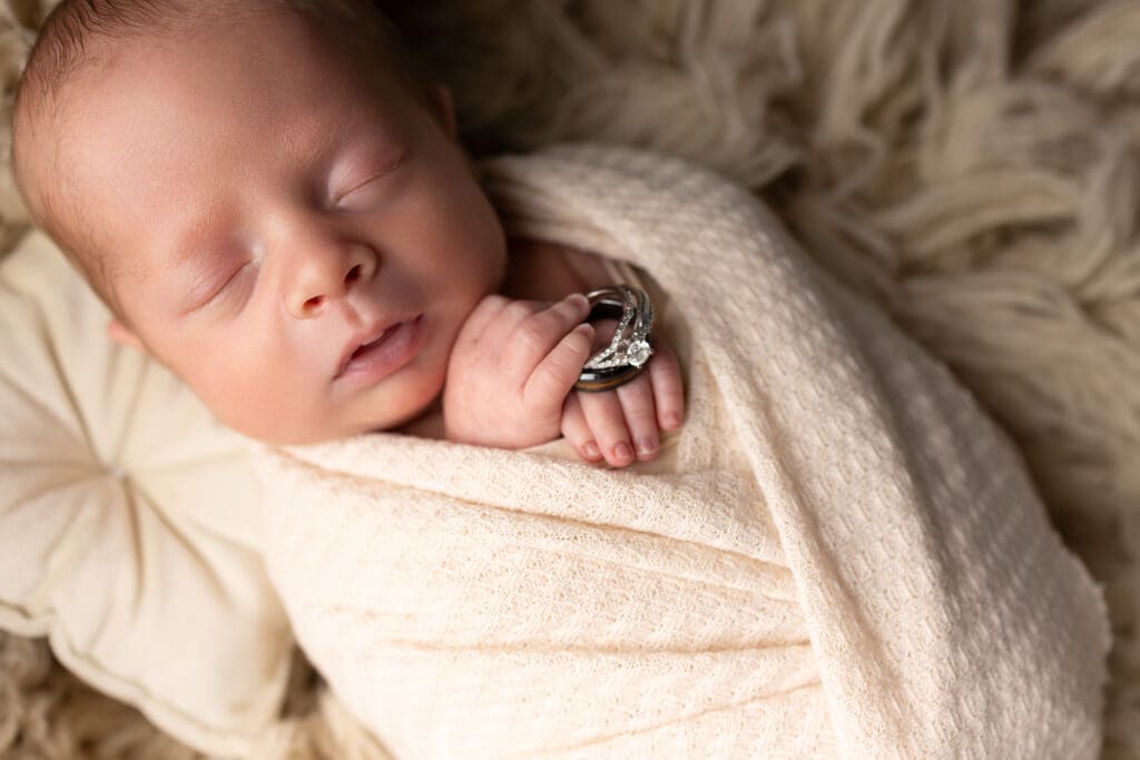 Newborn baby holding mom and dad wedding rings for Lehigh Valley newborn photography.