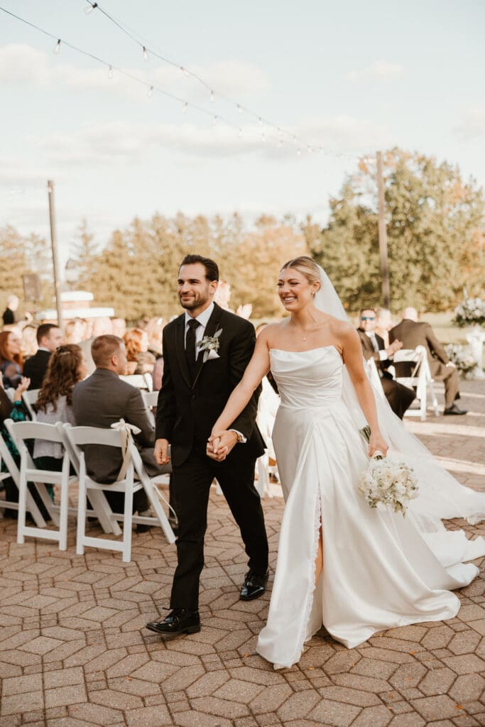 Bride and groom walk down the aisle of courtyard ceremony at Brookside Country Club wedding venue. 