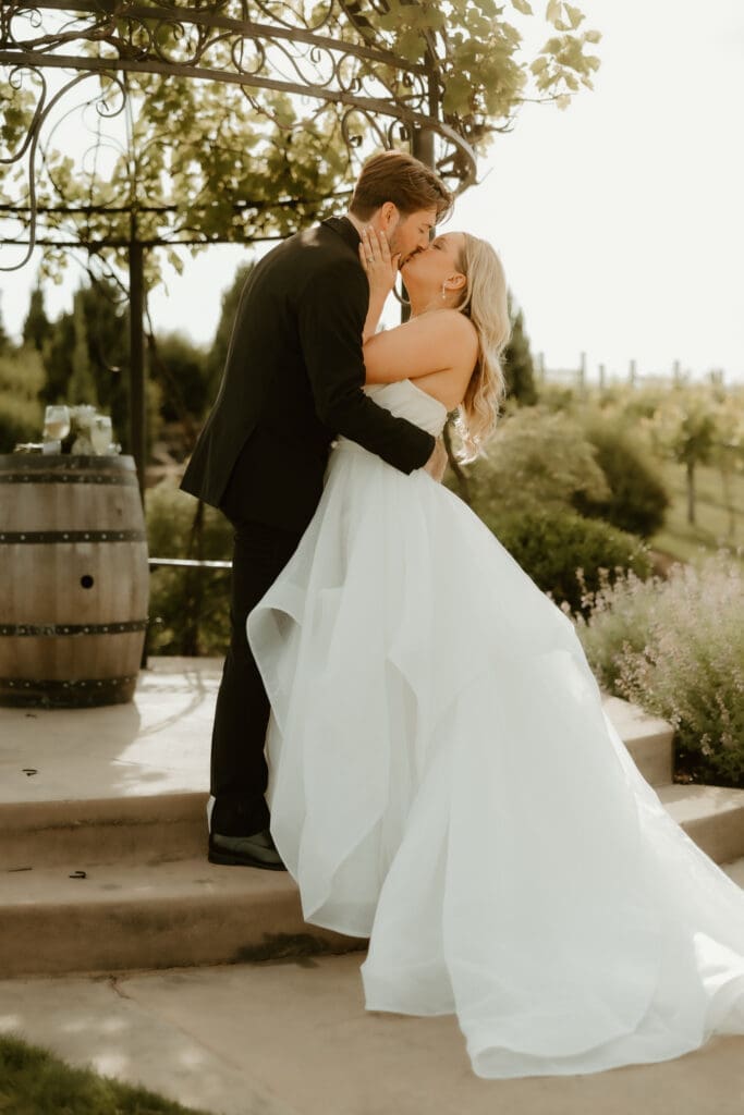 Bride and groom share first kiss at Folino Estate outdoor wedding arch in Kutztown PA.